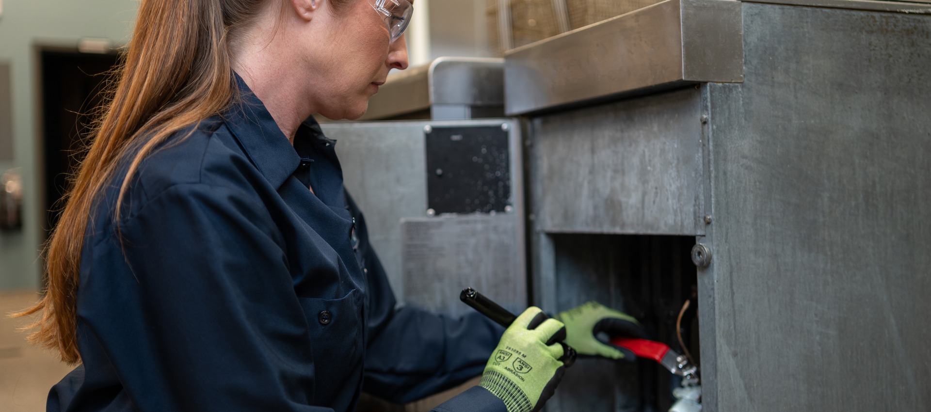 Facilities Management technician in work gloves servicing commercial kitchen equipment