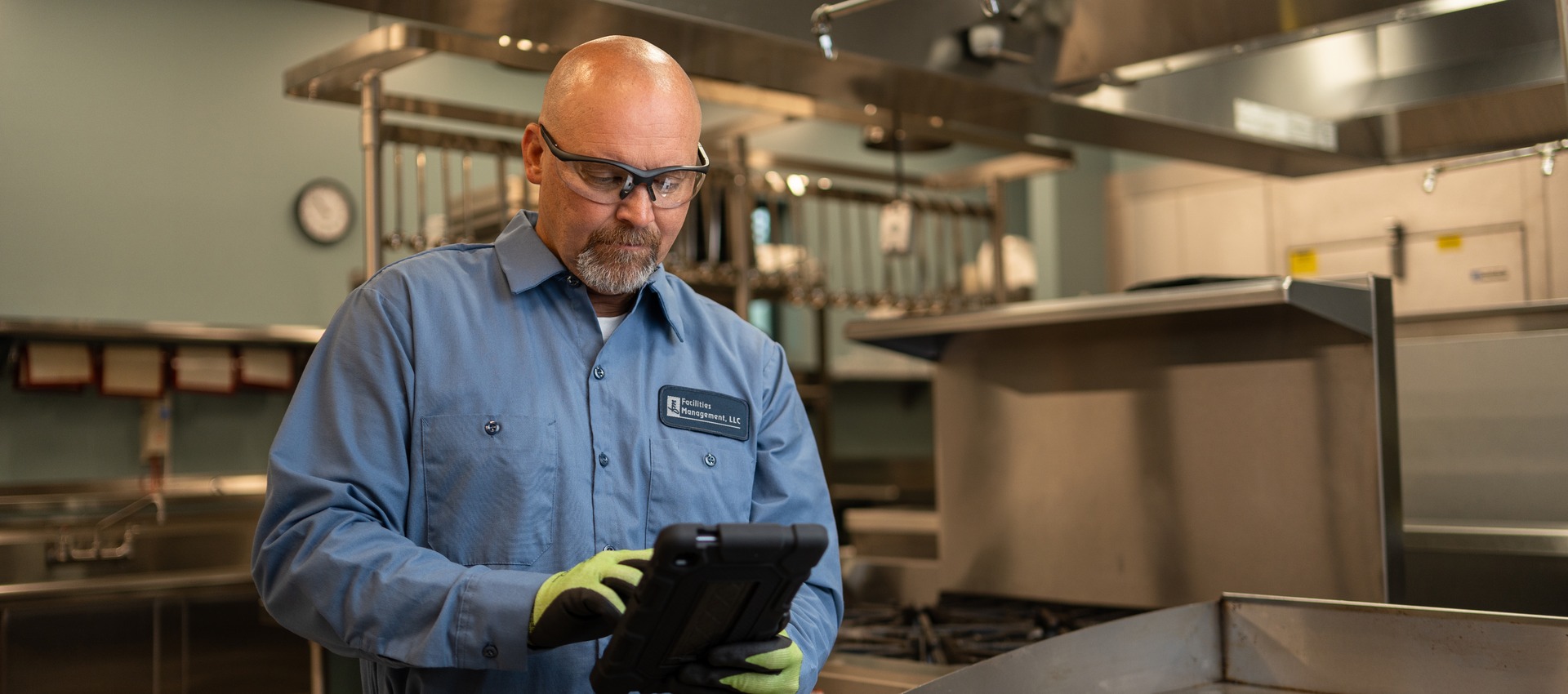 Facilities Management technician reviewing a service tablet in a commercial kitchen