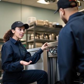 Facilities Management technician explaining a piece of commercial kitchen equipment to a colleague during training