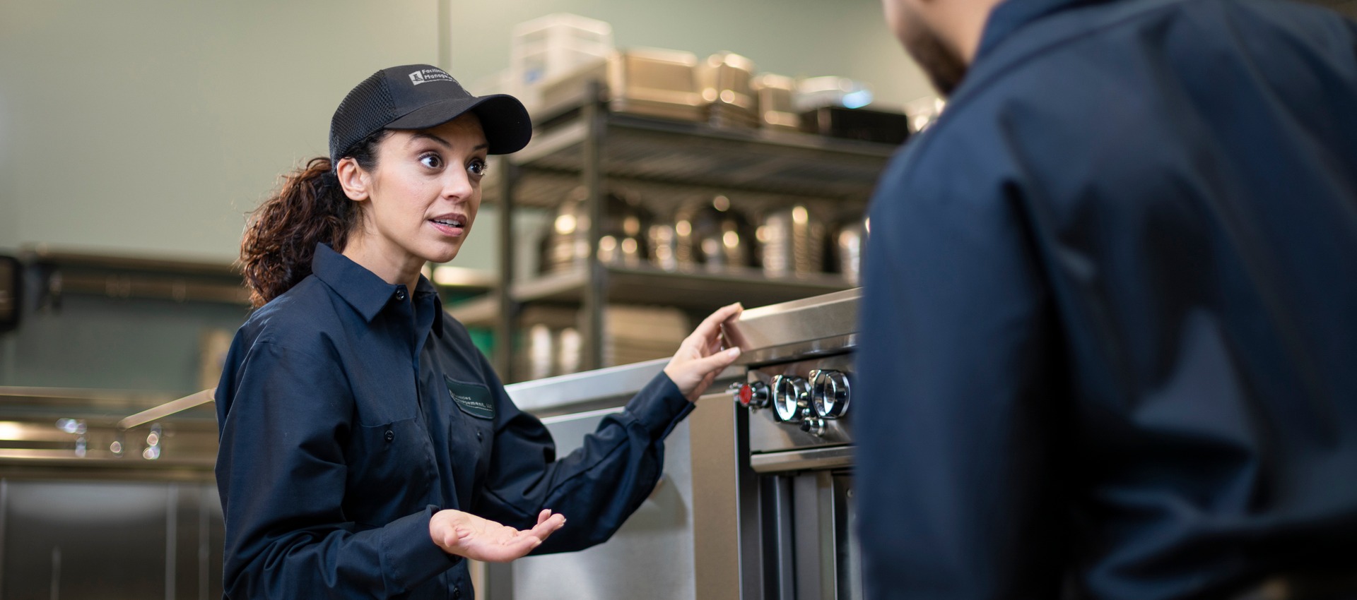 Facilities Management technician explaining a piece of commercial kitchen equipment to a colleague during training