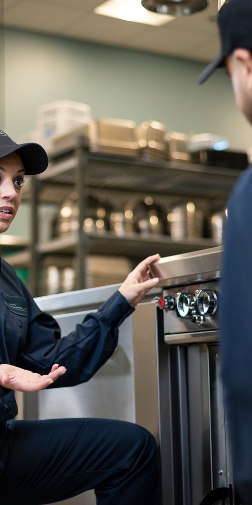 Facilities Management technician explaining a piece of commercial kitchen equipment to a colleague during training