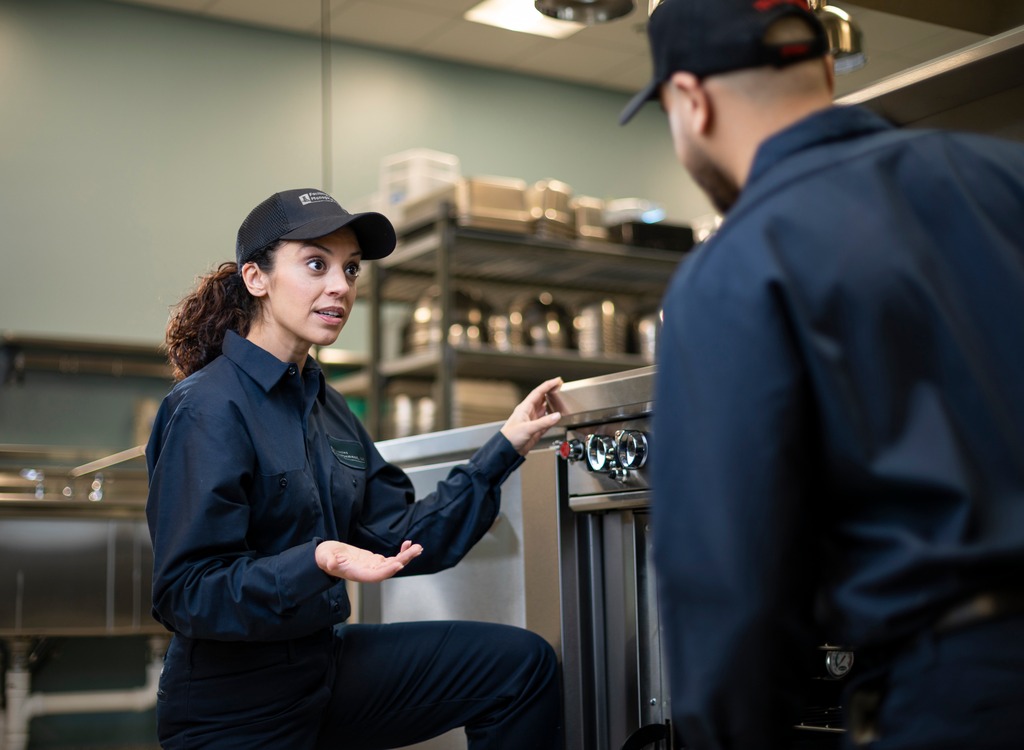 Facilities Management technician explaining a piece of commercial kitchen equipment to a colleague during training
