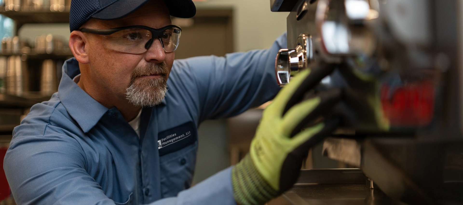 Facilities Management technician in a cap repairing commercial foodservice equipment