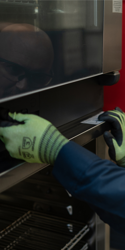 Technician in safety glasses inspecting a commercial oven door