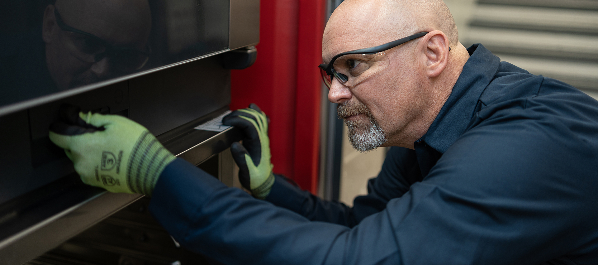 Technician in safety glasses inspecting a commercial oven door