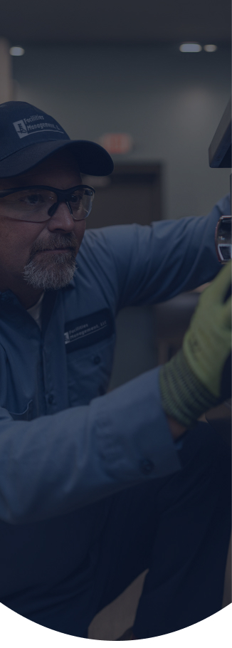 Facilities Management technician in a cap repairing commercial foodservice equipment