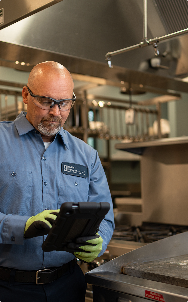 Facilities Management technician reviewing a service tablet in a commercial kitchen